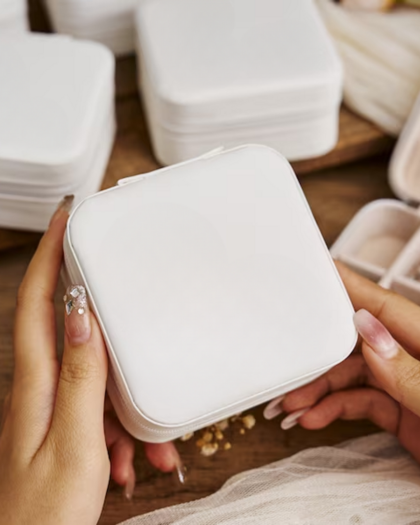 White jewelry case held by hands on a wooden surface