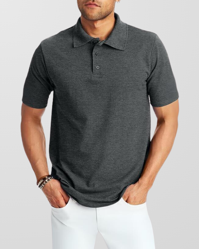 A man wearing a white customized polo shirt with short sleeves, standing with hands in pockets.